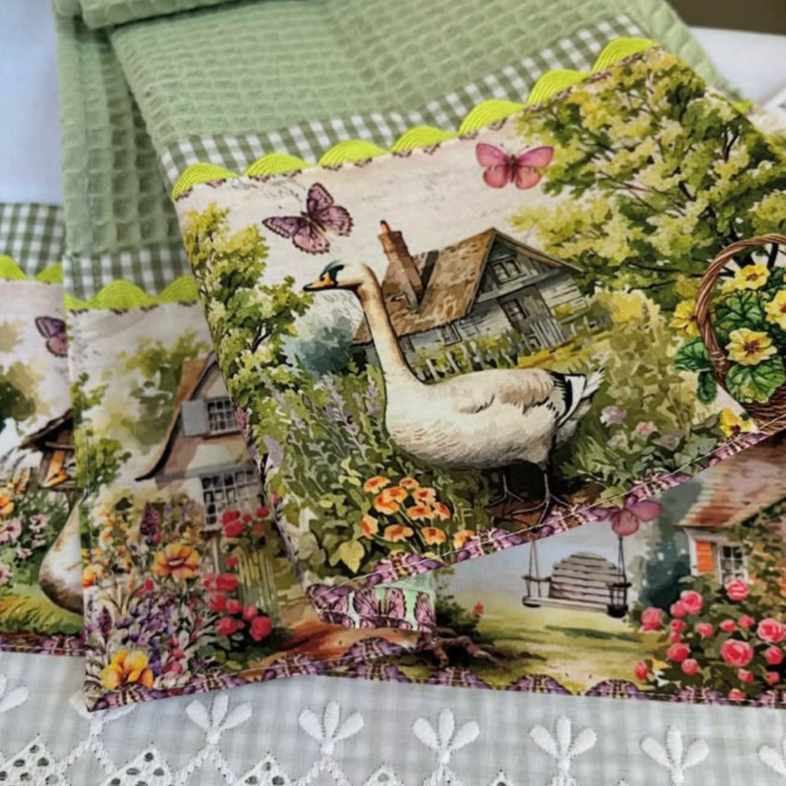 Sage green waffle-weave towel and coordinating white towel with goose and cottage garden print, green gingham and white eyelet trim.