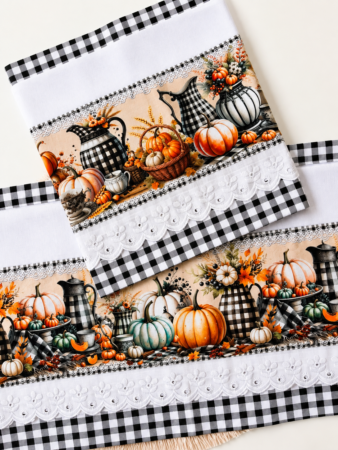 Set of two Pumpkin Harvest tea towels laid flat on a white surface showing the full buffalo check pitcher and colorful pumpkin print panel with white eyelet lace and black gingham trim
